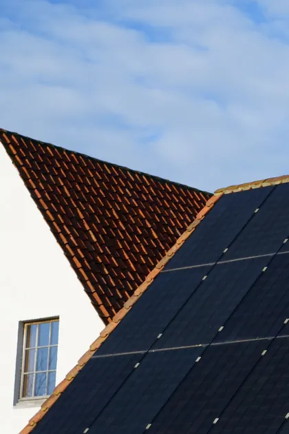 Satteldach mit schwarzen Solarmodulen vor blauem Himmel